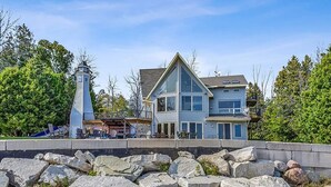 Ein Küstenhaus mit Leuchtturm, großen Fenstern und einem Balkon.