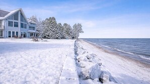 Ein schneebedeckter Strand mit einem Haus und Bäumen im Hintergrund.