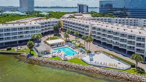 Un hotel moderno de altura con varios balcones, una piscina central y vistas de la ciudad circundante.