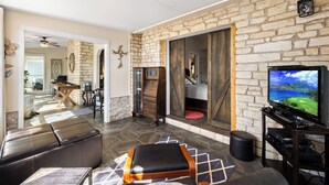 Una sala de estar moderna con una pared de piedra, un televisor y una chimenea.