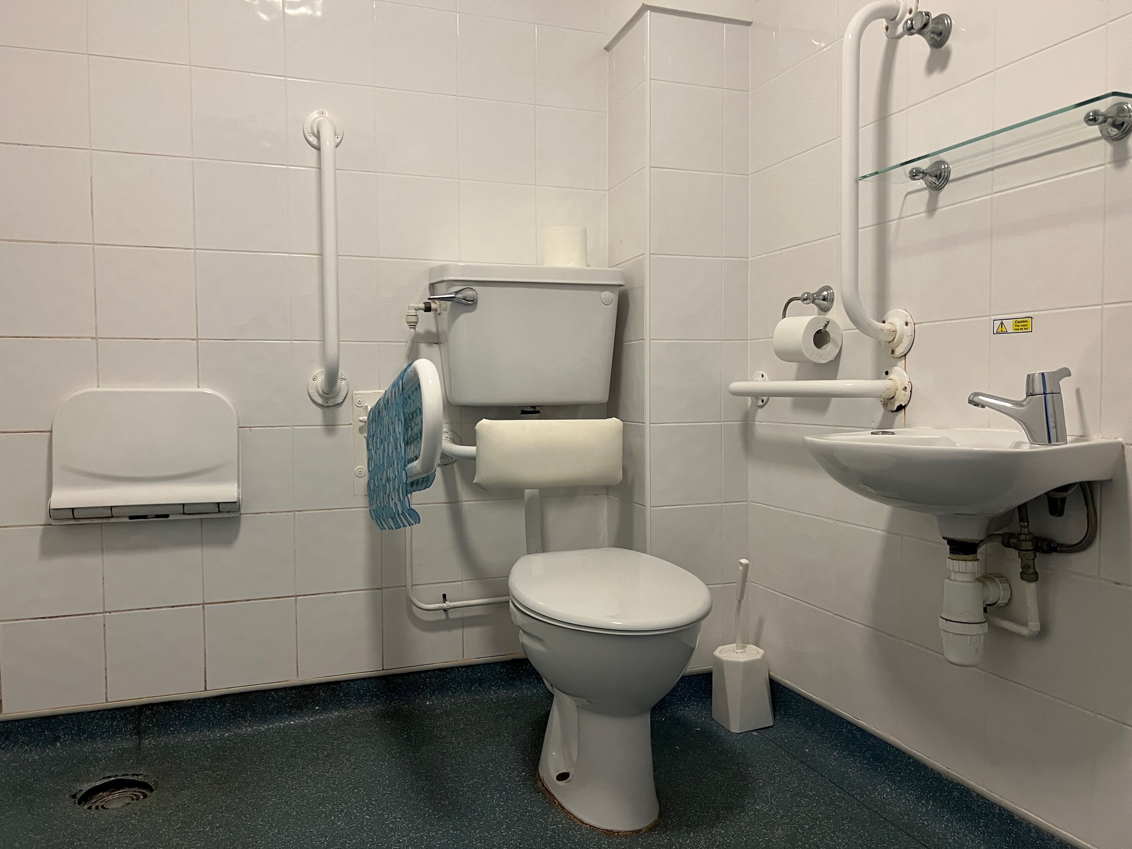 A bathroom with a toilet, sink, and hand dryer.