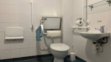 A bathroom with a toilet, sink, and hand dryer.