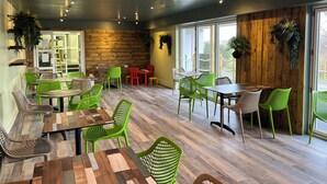 A restaurant with wooden walls, green chairs, and tables. - Hot Tub Haven with Dreamy Sea Vista! (Ilfracombe)