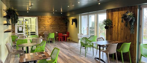 A restaurant with wooden walls, green chairs, and tables.