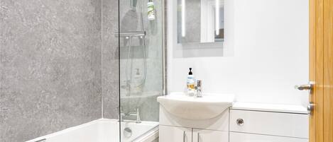 A modern bathroom with a glass-enclosed shower, a white sink, and a toilet.