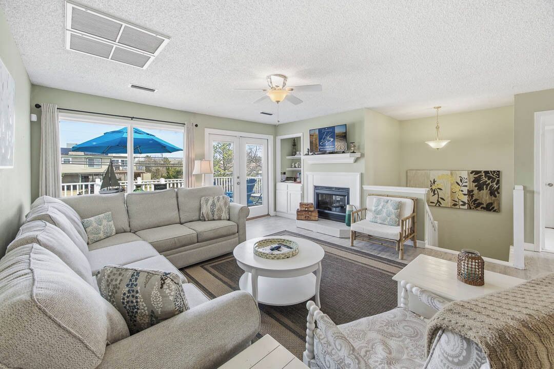 A living room with a sofa, coffee table, fireplace, and a view of the outside.