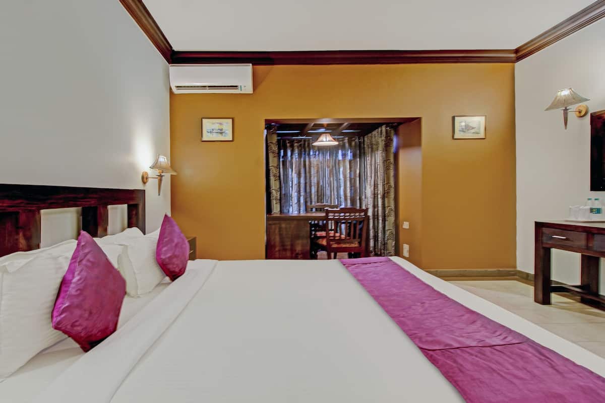 A hotel room with a large bed, a desk, and a chair.