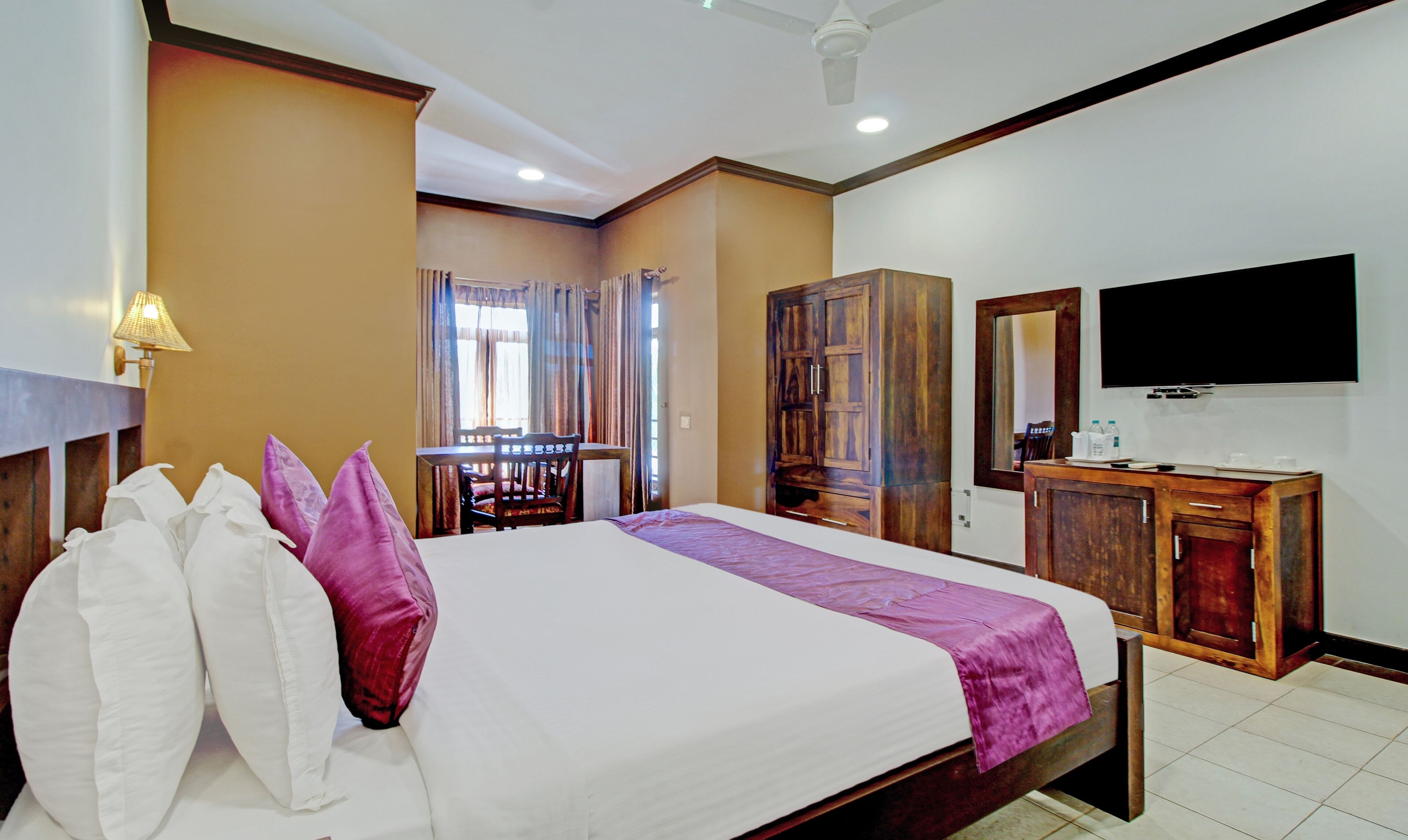 A hotel room with a bed, a desk, a wardrobe, and a TV.