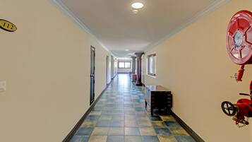 A hallway with a checkered floor, a fire extinguisher on the right, and a door on the left.