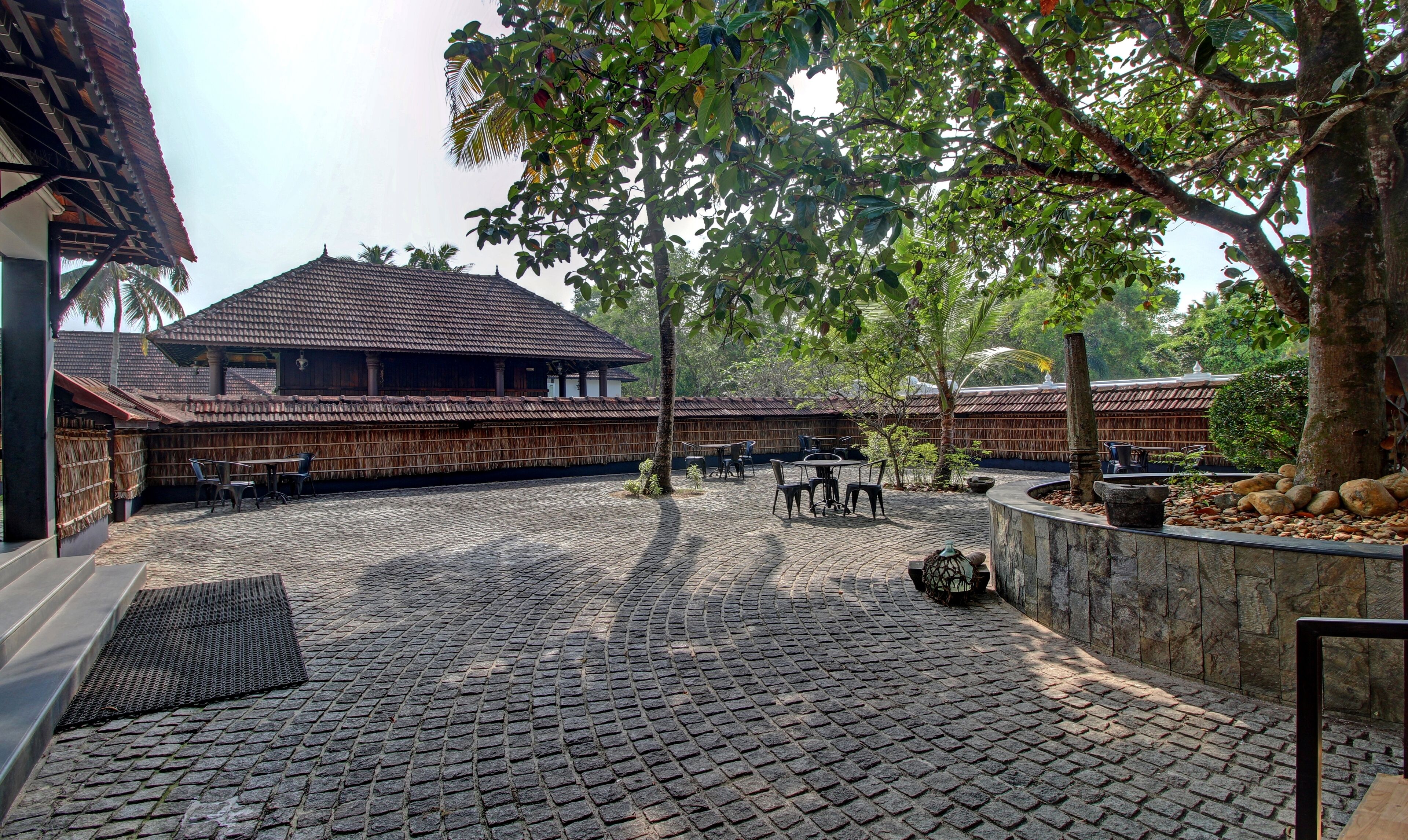 A courtyard with a traditional building, cobblestone flooring, and outdoor seating.