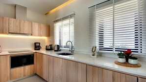 Une cuisine moderne avec des meubles en bois, un four à micro-ondes encastré, une machine à café et un évier.