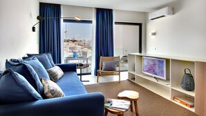 Un salon moderne avec un canapé bleu, un téléviseur et un fauteuil en osier.