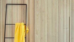 Une pièce avec un mur en bois et un étagère en métal noir sur laquelle est posée une serviette jaune.