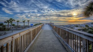 A wooden boardwalk leading to a beach with palm trees and a sunset. - Golf Cart ~ Seasonally Heated Pool ~ First Floor (Miramar Beach)