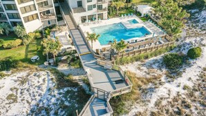 An aerial view of a resort with a large pool, multiple decks, and surrounding greenery. - Golf Cart ~ Seasonally Heated Pool ~ First Floor (Miramar Beach)