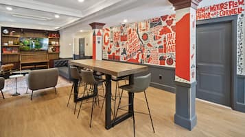 A modern dining area with a wooden table and chairs, a television, and a wall with red and black decor.