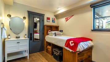 Un dormitorio pequeño con una cama, un tocador con espejo, un armario y una ventana.