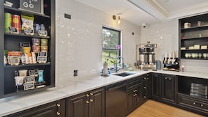 Una cocina moderna con armarios oscuros, una encimera blanca y una máquina de café.