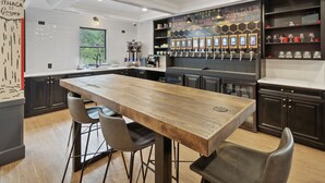 Una cocina moderna con una isla central, zona de bar con grifos y un menú en una pizarra.