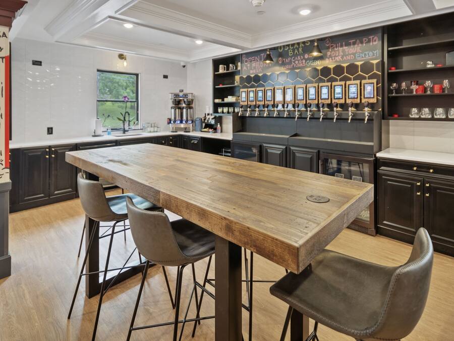 A modern kitchen with a central island, bar area with tap handles, and a chalkboard menu.
