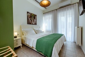 A bedroom with a bed, a nightstand, a lamp, a wall-mounted air conditioner, and a window with curtains.