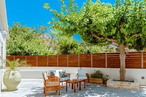An outdoor patio with wooden furniture, a large tree, and a wooden fence.