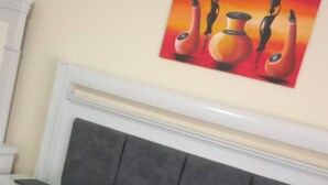 Une chambre à coucher avec un lit, une table de chevet et un tableau accroché au mur.