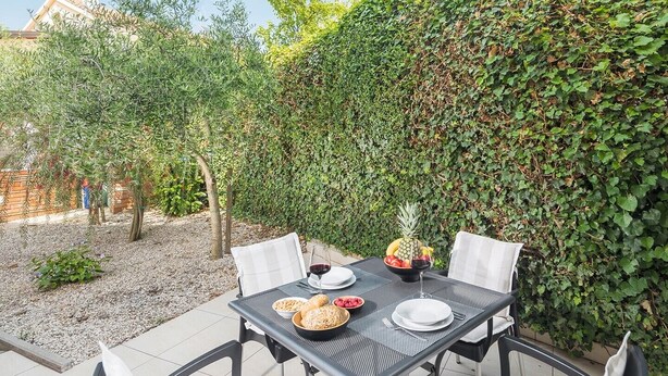 Un espace extérieur aménagé pour prendre les repas, avec une table dressée pour deux personnes, entourée de chaises.