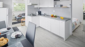 Une cuisine moderne avec des meubles blancs, un plan de travail gris et un coin repas avec une table dressée pour deux personnes.
