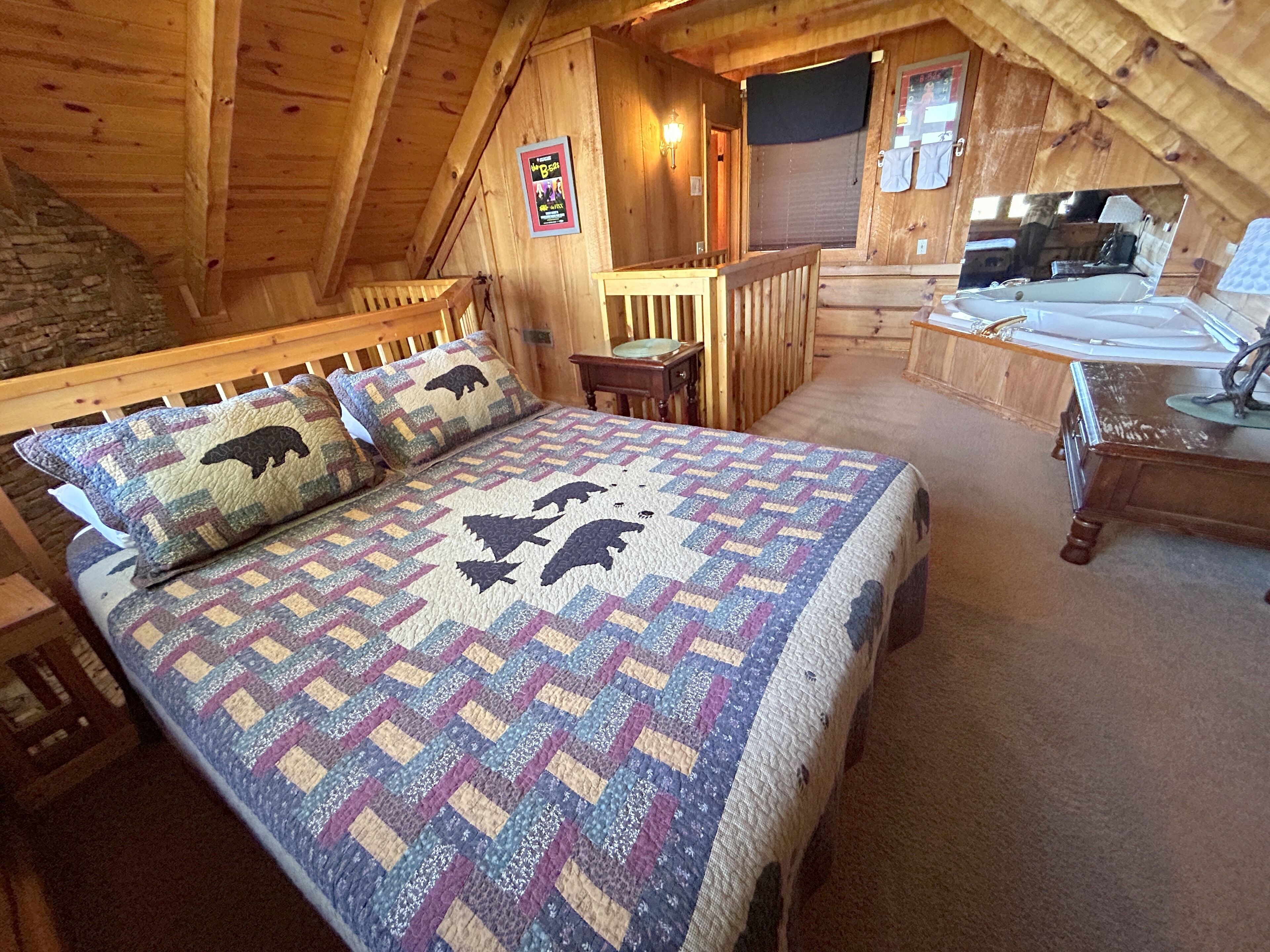 Un dormitorio acogedor en el ático con una cama de madera, un escritorio pequeño y una pared de piedra.