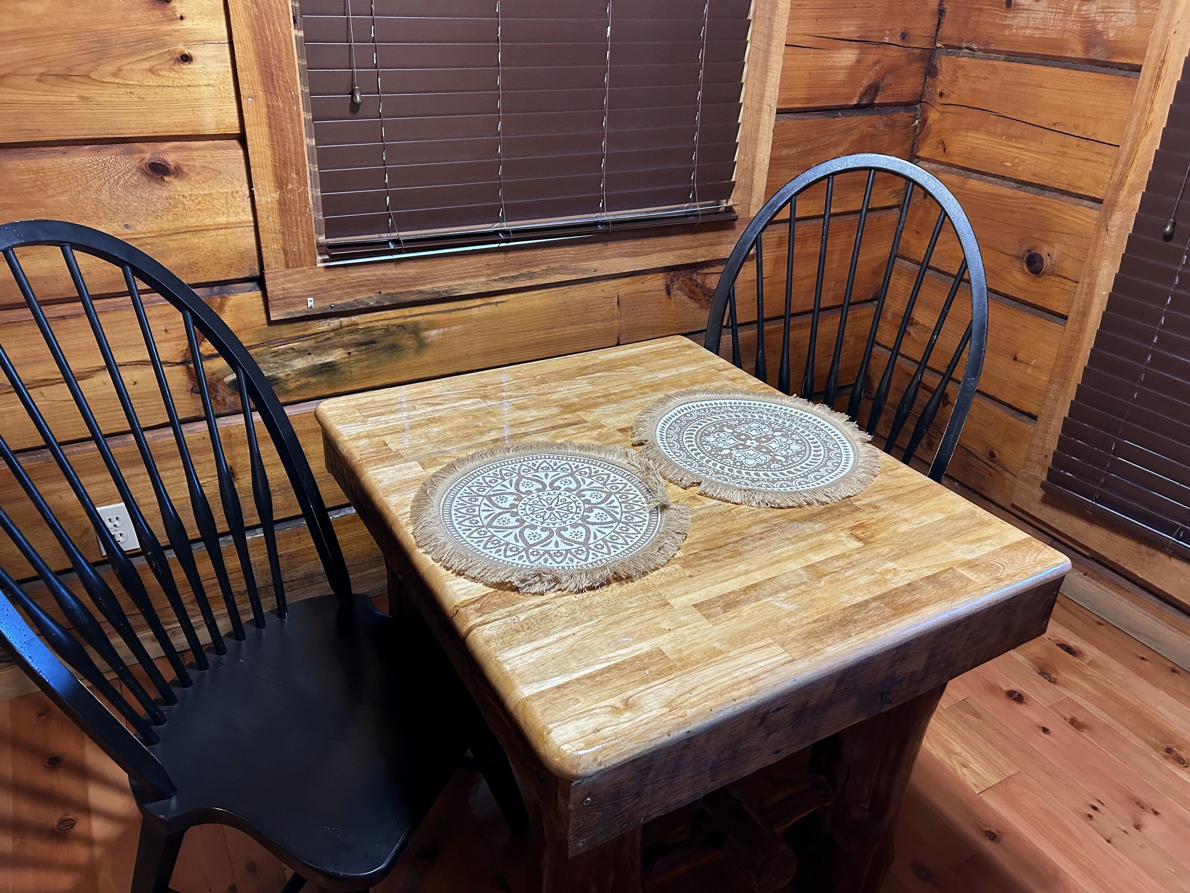 A wooden table with two chairs, each with a circular, patterned placemat.
