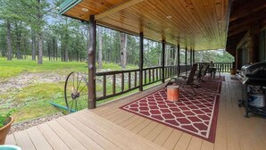 Une véranda couverte avec une terrasse en bois, un espace salon extérieur et un coin barbecue.
