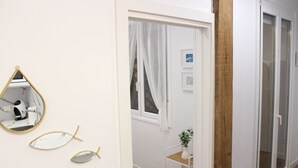 Ein Flur mit einer weißen Tür, einem Spiegel und einem Blumentopf.