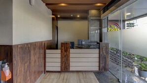 Ein Empfangsbereich mit modernem Design, inklusive einer Holztresen, einer Glastrennwand und Blick ins Freie.