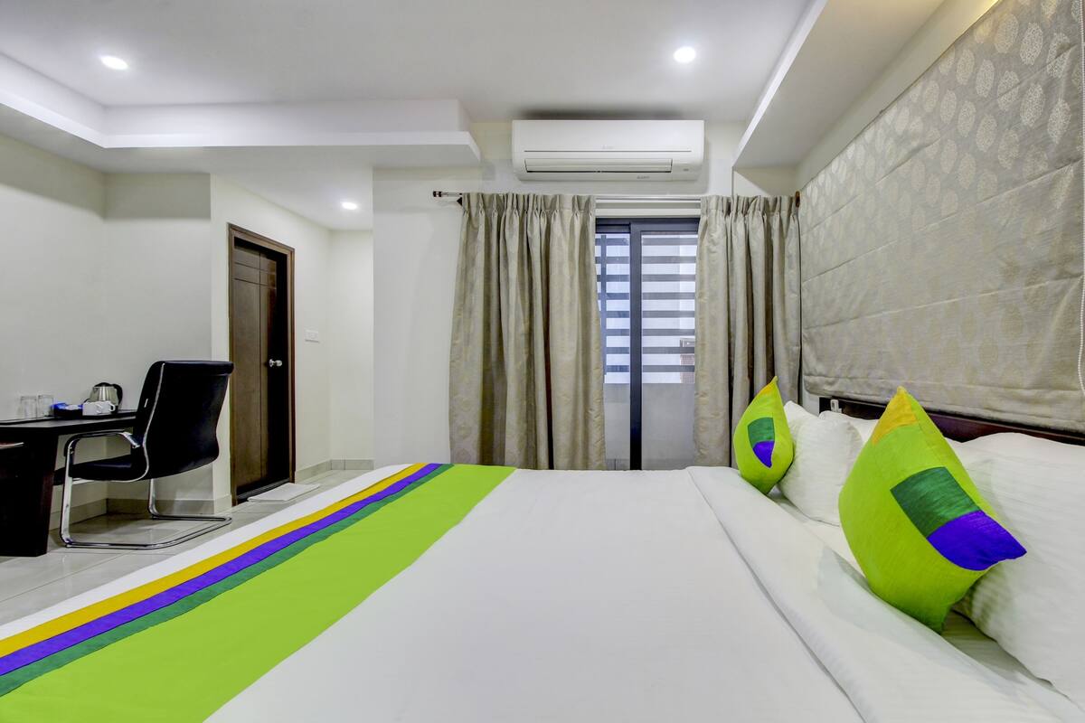 A hotel room with a bed, a desk, and a chair.