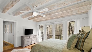 Een slaapkamer met een groot bed, een plafondventilator, een dressoir en een televisie.