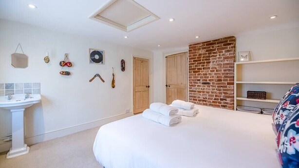 A bedroom with a large bed, a white sink, a brick accent wall, and various wall decorations.