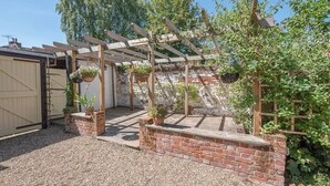 A covered patio area with a brick wall, wooden pergola, and hanging planters.