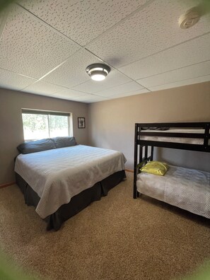 A bedroom with a bunk bed, a single bed, a window, and a ceiling light fixture. - Peaceful and private with quick access to all the Black Hills has to offer! (Rapid City)