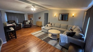A modern living room with a sectional sofa, a coffee table, a desk with a chair, and a ceiling fan. - Peaceful and private with quick access to all the Black Hills has to offer! (Rapid City)