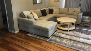 A modern living room with a sectional sofa, a round coffee table, and a rug. - Peaceful and private with quick access to all the Black Hills has to offer! (Rapid City)