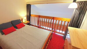 A bedroom with a bed, nightstands, a wooden headboard, a balcony, and a lamp.