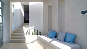 Un interno moderno con una scala che conduce a una zona pranzo, un angolo relax con cuscini e un design minimalista.