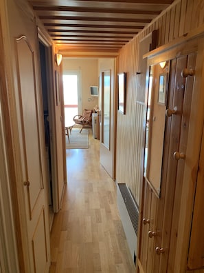 A wooden hallway with a ceiling of horizontal beams, leading to a room with a chair and a television. - Appartement à 2 Minutes à Pied des Commerces et Télécabines Avec Superbe vue (Font-Romeu-Odeillo-Via)