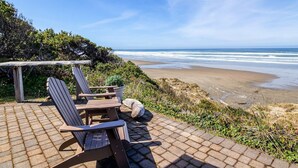 A beachside seating area with Adirondack chairs and a pergola overlooking the ocean. - Ocean Front with Beautiful Views! Miles of Sandy Beach! (Seal Rock)