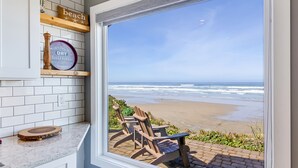 A kitchen with a view of the beach, a wooden chair, and a sign that says "Morning Side Roast Coffee". - Ocean Front with Beautiful Views! Miles of Sandy Beach! (Seal Rock)