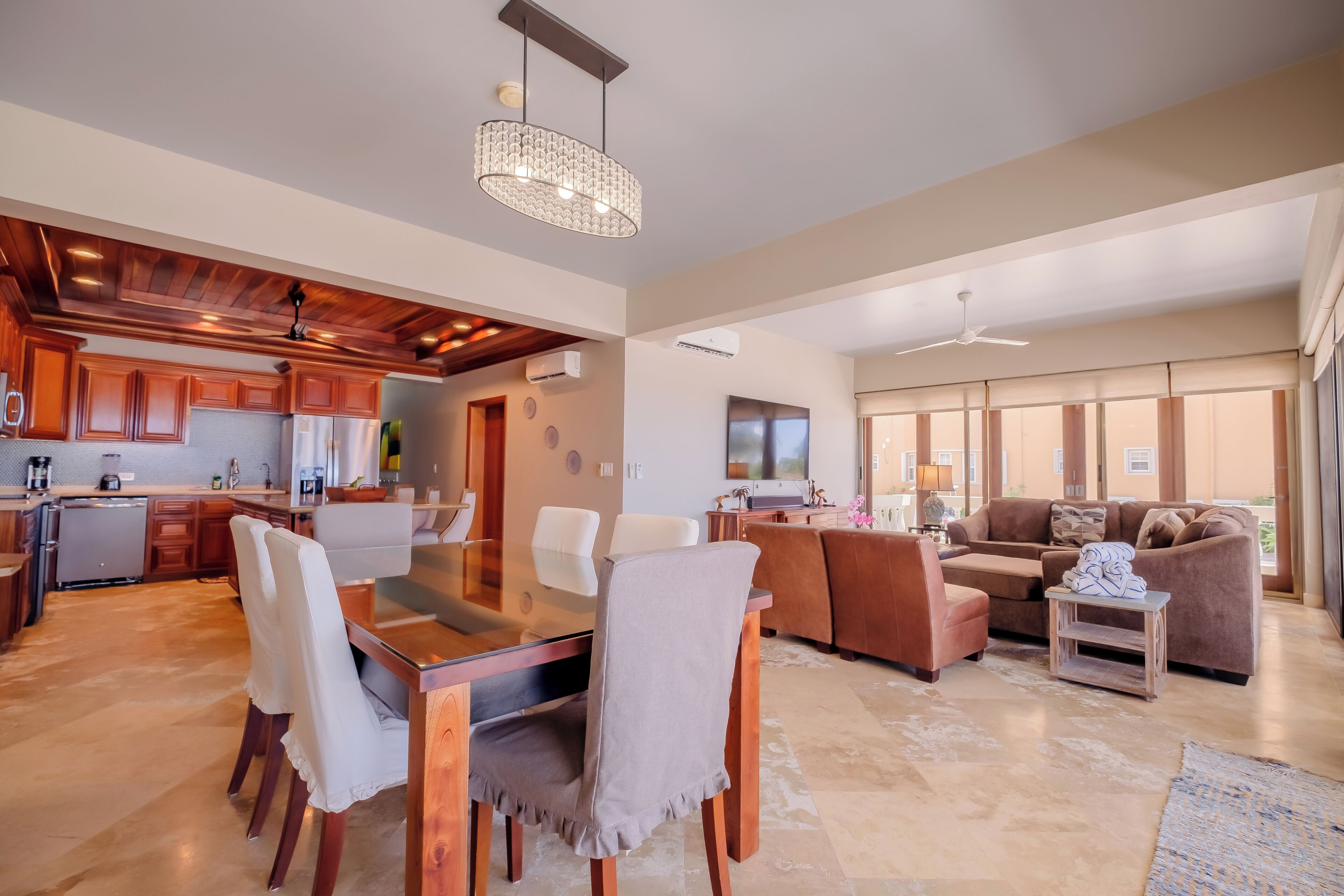 A spacious living area with a dining table, sofas, and a kitchen in the background.