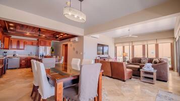 A spacious living area with a dining table, sofas, and a kitchen in the background.