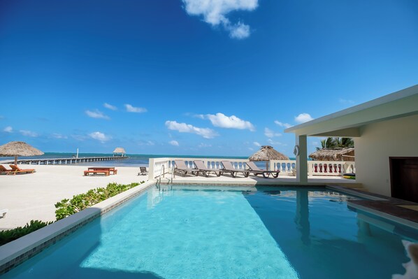 A pool area with lounge chairs and a view of the beach.