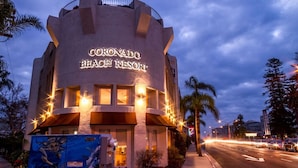 The exterior of Coronado Beach Resort with a prominent sign, a curved facade, and a well-lit entrance.